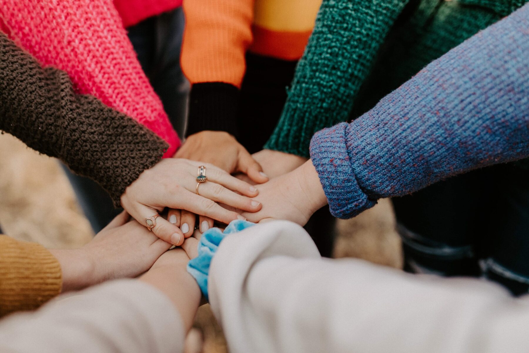 A group of people placing their hands together in the middle of a circle